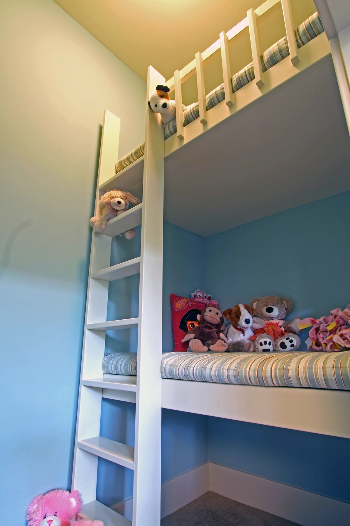 A custom built-in kids' bunk with an integrated ladder against blue walls.